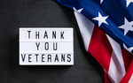 American flag on a dark background. "Thank you Veterans" written on light board.